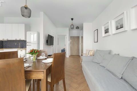 A bright and airy living room with a wooden dining set and modern gray sofa. A functional and inviting space for guests.