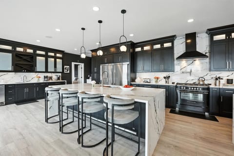 View of one island in the expansive ktichen, along with the two size-by-side fridge/freezer units and cooktop with oven