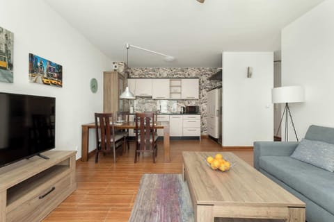 A bright and airy living room with a grey sectional sofa and rustic-style dining table, perfect for social gatherings.