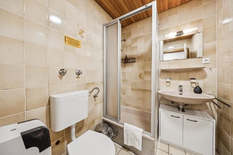 Helles Bad mit Dusche, Waschtisch und WC in klassisch gefliester Optik – funktional und gepflegt für die Ferienwohnung.