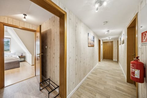 Heller Flur mit Holzdekor, modernen Deckenleuchten und offenem Zugang zum Schlafzimmer – einladender Bereich der Ferienwohnung.