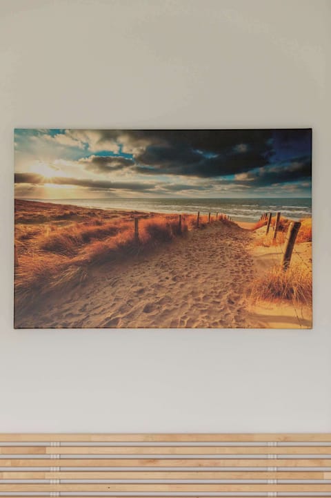 A wall-mounted photo featuring a scenic beach path, framed with a light-colored border.