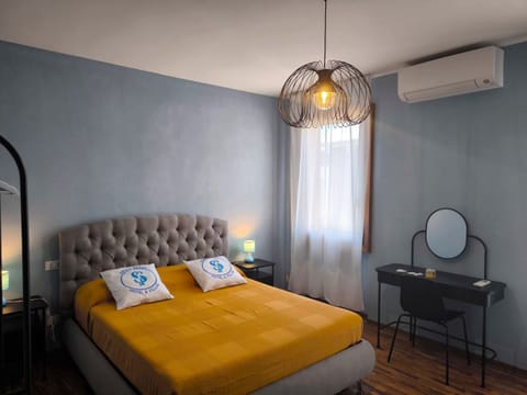 Double bedroom in the apartment in Peschiera del Garda, furnished in a modern style with relaxing tones. The large, comfortable bed, warm lighting, and desk with mirror create a welcoming and refined atmosphere, ideal for relaxing after a day at the lake.