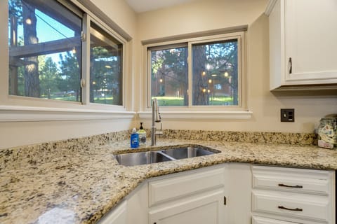 Corner kitchen sink framed by two bright windows offering serene outdoor views.