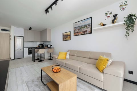 A cozy modern living room with a sofa, colorful wall art, and a wooden coffee table.