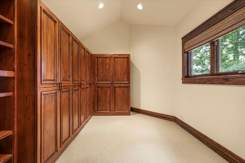 Closet: Spacious walk-in closet with custom wood cabinetry, built-in shelving, and natural light