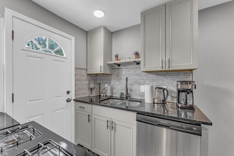 Sleek kitchen with stainless steel appliances and sink   - Stylish backsplash with modern cabinets and storage   - Coffee maker and essentials ready for your stay