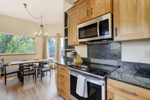Modern kitchen with stainless steel appliances, black tile backsplash, and easy flow into the bright dining area with outdoor views.