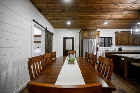 Wood beams, granite island, barn door—warm dining space with cozy charm