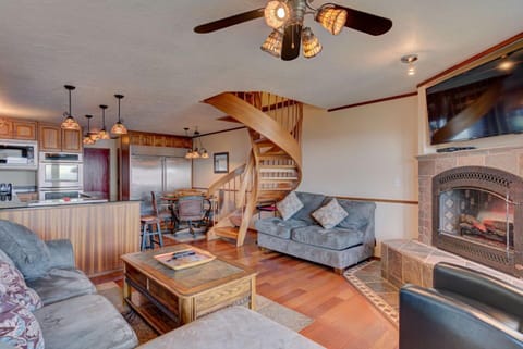 The Gathering Place features a spacious living room with a cozy sectional sofa, a beautiful spiral staircase leading to the upper level, and a gourmet kitchen equipped for delightful meals.