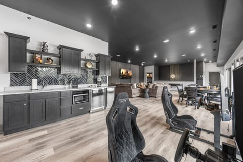 Enjoy a sleek, modern entertainment space featuring a fully equipped kitchenette, comfortable seating area, and multiple gaming setups. Perfect for relaxing, socializing, and enjoying your favorite games in a stylish, open-concept environment.