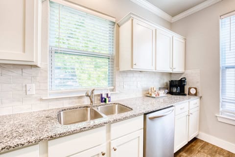Bright, fully equipped kitchen with granite countertops, double sink, full‑size dishwasher and a coffee station.