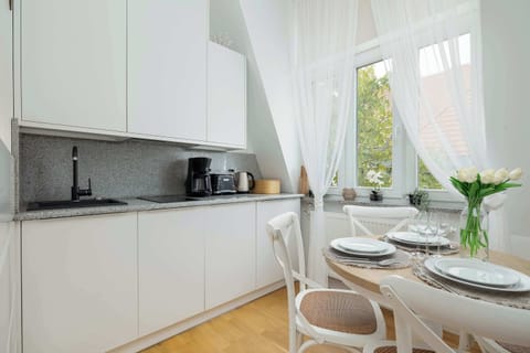 A compact kitchen area with modern appliances. White curtains flow gently by the window.