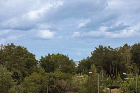 A scenic view of green treetops under a blue sky. Nature surrounds the apartment complex.