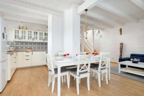 A dining room with a long wooden table and white chairs under a slanted ceiling.