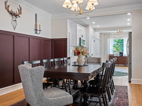 Spacious dining area with seating for large groups, perfect for shared meals or game nights, featuring stylish wood paneling and warm lighting.