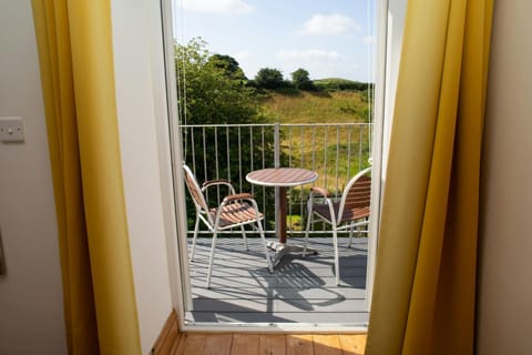 Kingsize bedroom with doors leading to a balcony with bistro table and chairs