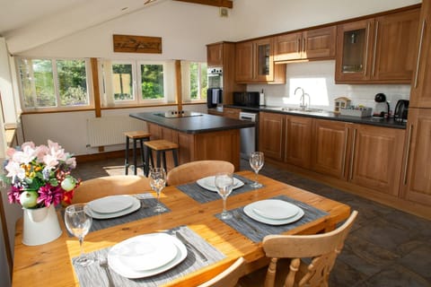 Kitchen with island with stools and dining table. Views over the gardens