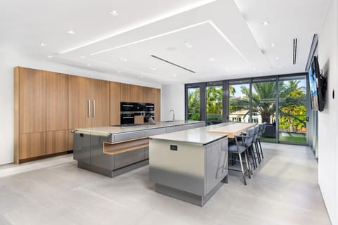 Modern kitchen setup featuring sleek counters, large breakfast island, and panoramic window outlook