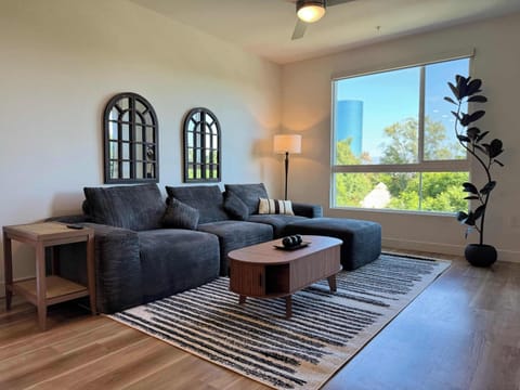 Spacious living room featuring a cozy L-shaped sofa, a full-size air mattress, and a 65" Smart TV with preloaded access to Netflix, Hulu, and Disney+, all set up for your enjoyment.