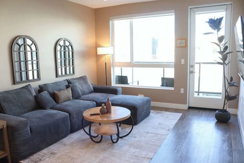 Spacious living room featuring a cozy L-shaped sofa, a full-size air mattress, and a 65" Smart TV with preloaded access to Netflix, Hulu, and Disney+, all set up for your enjoyment.