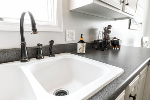 A deep double sink with a modern bronze faucet, stylish soap dispenser, and sleek countertops for all your washing and prepping needs.