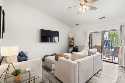 Living room with Smart TV, comfy sofas, and sliding door to patio