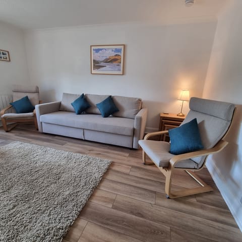 Living room and dining room with 3 seater sofa bed, easy chairs and large TV