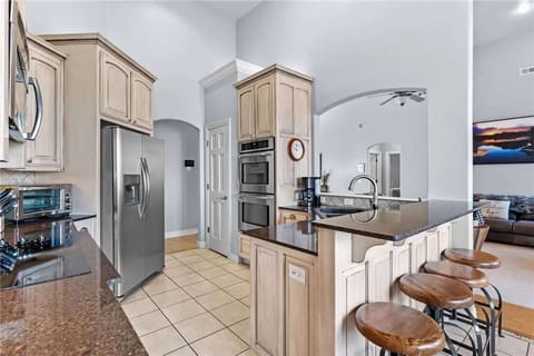 Bright modern kitchen and dining area with breakfast bar, stainless appliances, and ample lighting for cooking together.
