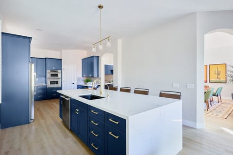 Stylish and functional kitchen with stainless steel appliances, navy cabinetry, marble countertops, and a spacious island with breakfast bar seating for 4.