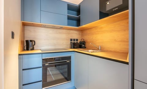 This modern kitchen boasts sleek blue cabinetry and a warm wood accent wall, making it both stylish and functional.