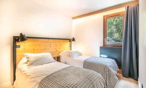 Natural light floods the second bedroom, highlighting the comfortable twin beds and tranquil decor.