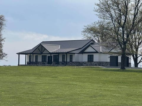 This close-up view highlights the beautiful architectural design and bold contrast of the black metal roof and stone accents. 

The wide porch and symmetrical layout give the home a clean and inviting presence.