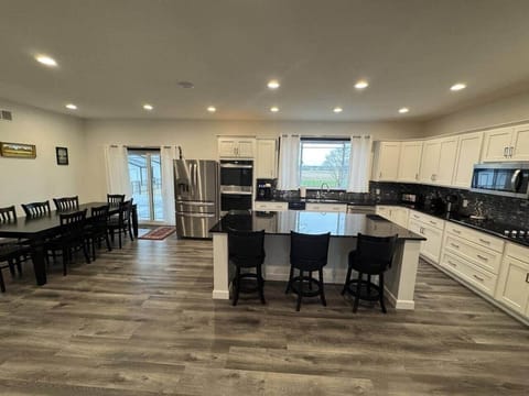 This is a front view showing the fully stocked kitchen complete with Amish cabinets, granite countertops, island with seating, and a dining room table with seating for 8.