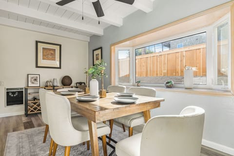 Bright, welcoming dining area featuring a rustic wood table, modern seating, and abundant natural light.