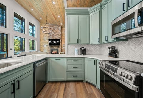 Soft green cabinets and modern finishes give the kitchen a fresh, calming feel that makes cooking a joy.