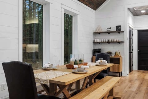 Rustic dining area with wood table, elegant décor, and natural light from large windows.