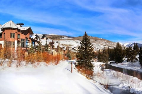 Stroll along the charming snow-covered pathway lined with luxurious townhomes, all beneath a brilliant blue sky, showcasing the resort's picturesque mountain setting.