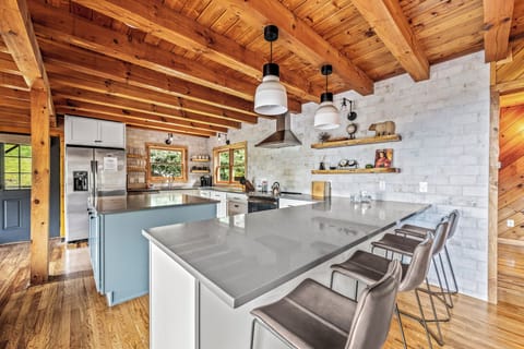Fully equipped, modern kitchen with open shelving and log beams.