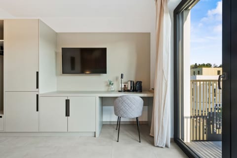 Functional Workspace and Entertainment Area – Wall-mounted TV, small desk, and a cozy chair create a perfect blend of comfort and productivity.