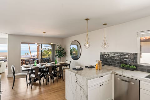 Stylish open-concept kitchen and dining area with marble island, modern lighting, and ocean views.