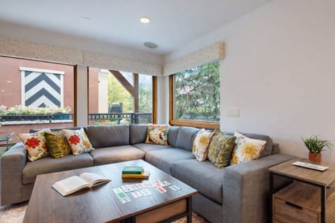 Sink into your spacious corner sofa with colorful throw pillows, where natural light streams through large windows overlooking leafy neighborhood views.