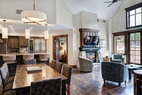 Spacious open-concept living and dining area accented with vaulted ceilings, a cozy fireplace, and elegant lighting for relaxed gatherings.