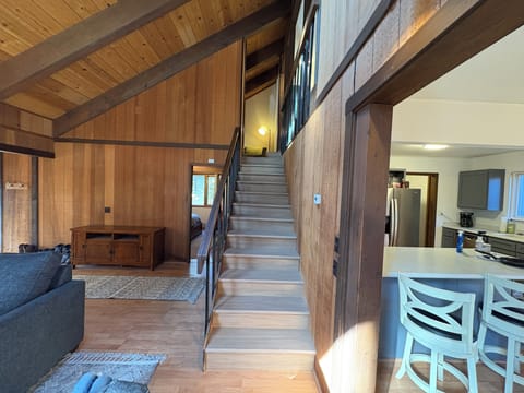 Unwind in your spacious open-plan living area featuring rustic wood beams, comfortable seating, and a warm mountain lodge atmosphere that flows seamlessly into the kitchen.