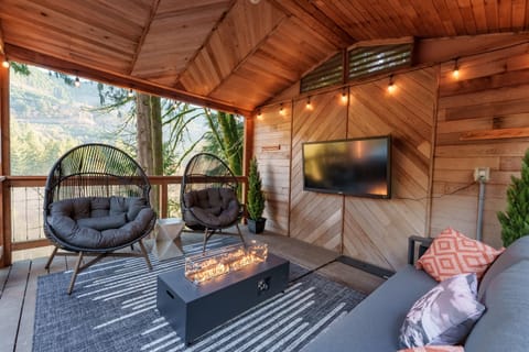 Settle into the covered deck lounge with cozy seating, a modern fire feature, and forest views—your perfect spot for movies, morning coffee, or unwinding after a day on the mountain.