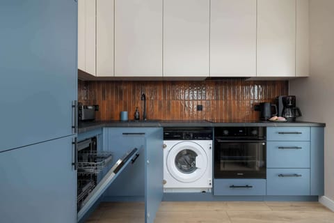 The modern blue cabinetry paired with a warm mosaic backsplash turns cooking into a pleasant and harmonious experience.