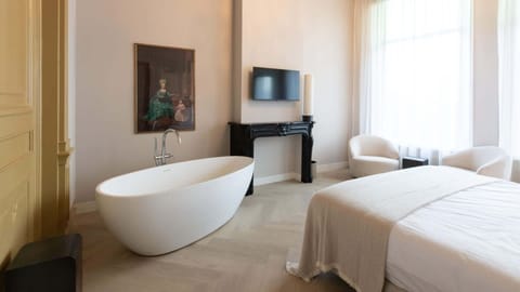 Freestanding tub, warm light and lounge area combined in a serene setting — perfect for slow mornings or unwinding at night.