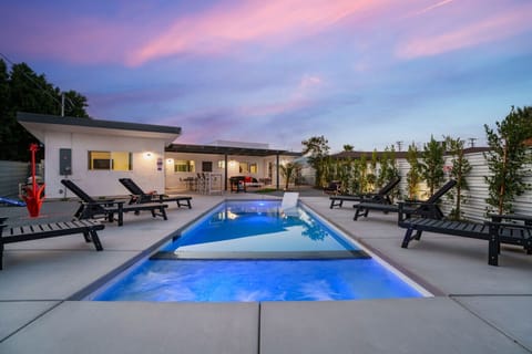 Resort-style pool glows at dusk, framed by lounge seating & desert landscaping for relaxed evenings outdoors
