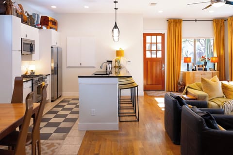 Your spacious open-plan living unfolds with modern kitchen, cozy seating, and warm golden accents creating the perfect retreat.