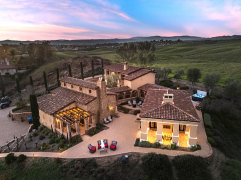 An illuminated estate set against rolling Temecula hills—where vineyard views and sunset skies set the tone for unforgettable evenings.